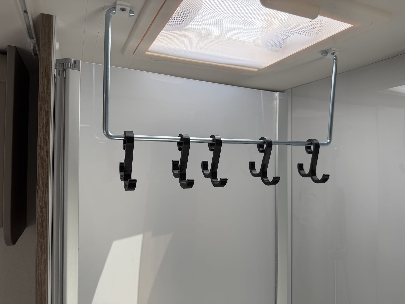 3D-gedruckte Haken auf einer Metallstange unter dem Dachfenster im Wohnmobil
